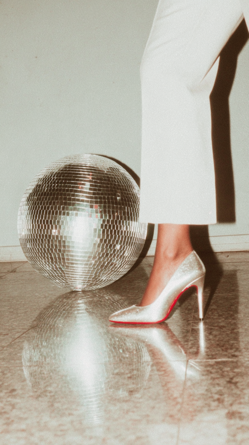 A mirror ball and a dancing shoe on a reflective floor